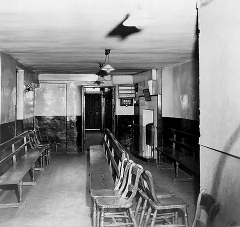 Sala de espera de una consulta médica antigua con bancos de madera.